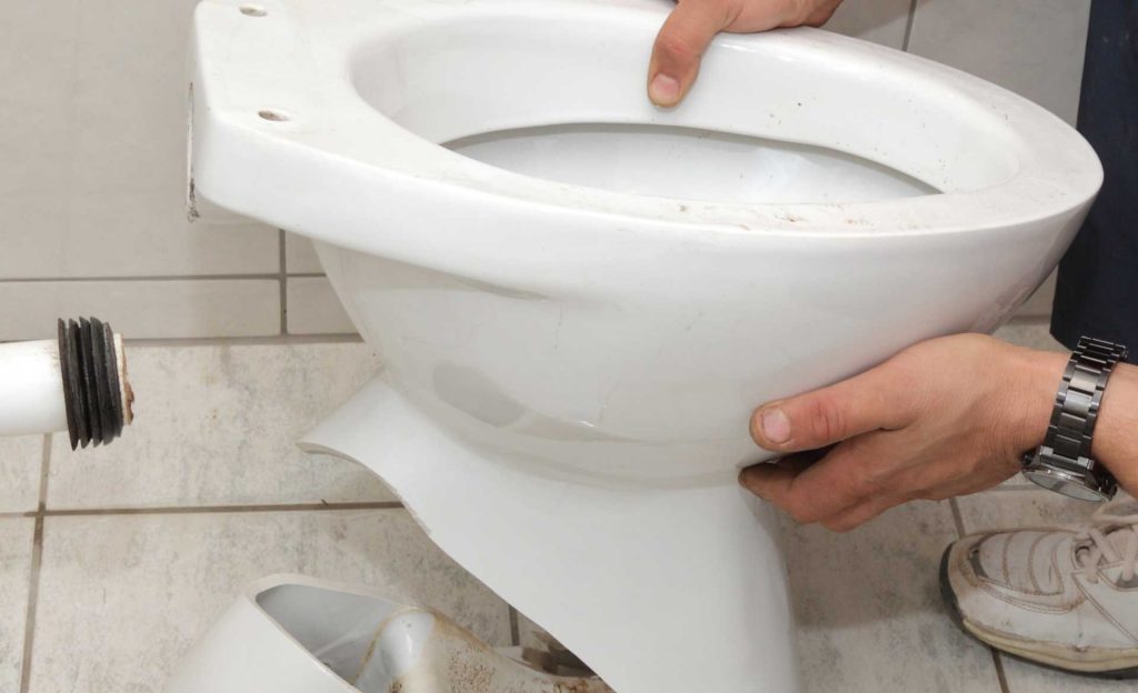 Plumber replacing toilet with cracked bowl